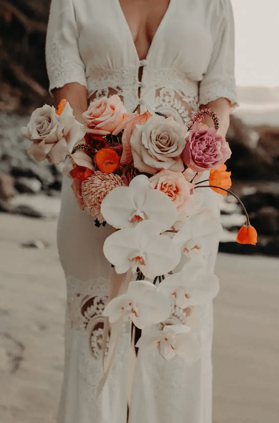 a cascading wedding bouquet of white orchids, pink, peachy, pale pink roses and orange touches is adorable