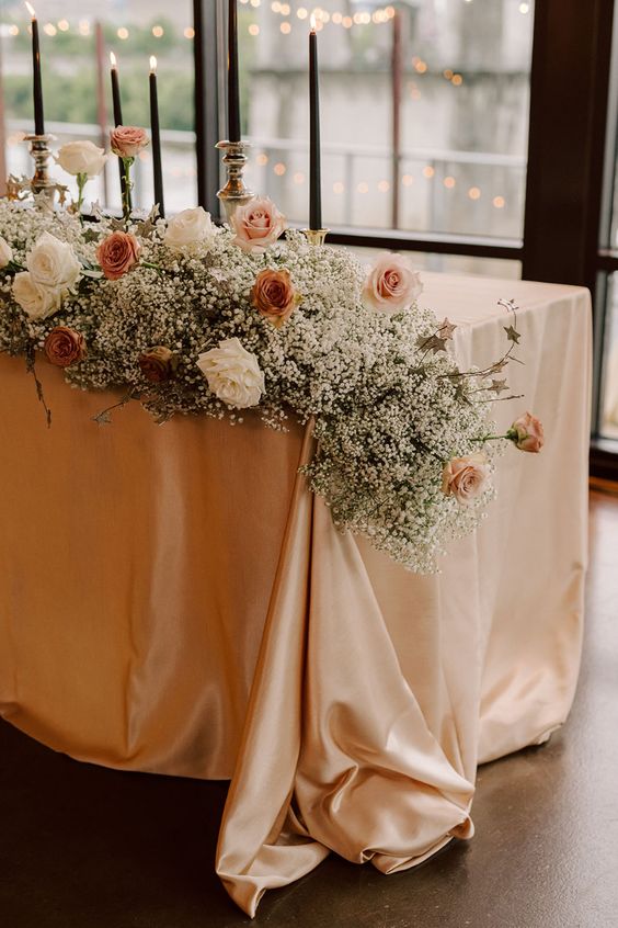 a cascading wedding centerpiece of baby's breath, white, blush and orange roses is a cool and chic decor idea that works for many weddings