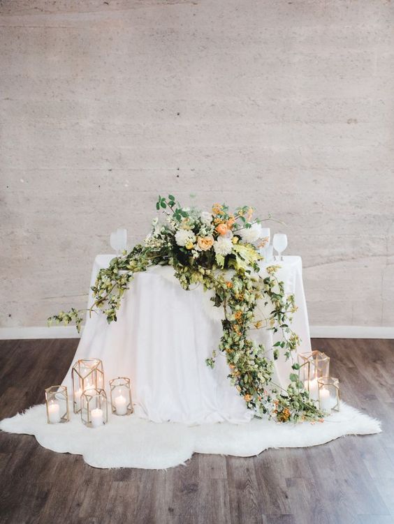 a cascading wedding centerpiece of white and oragne blooms and greenery is a super cool and catchy decoration for a wedding