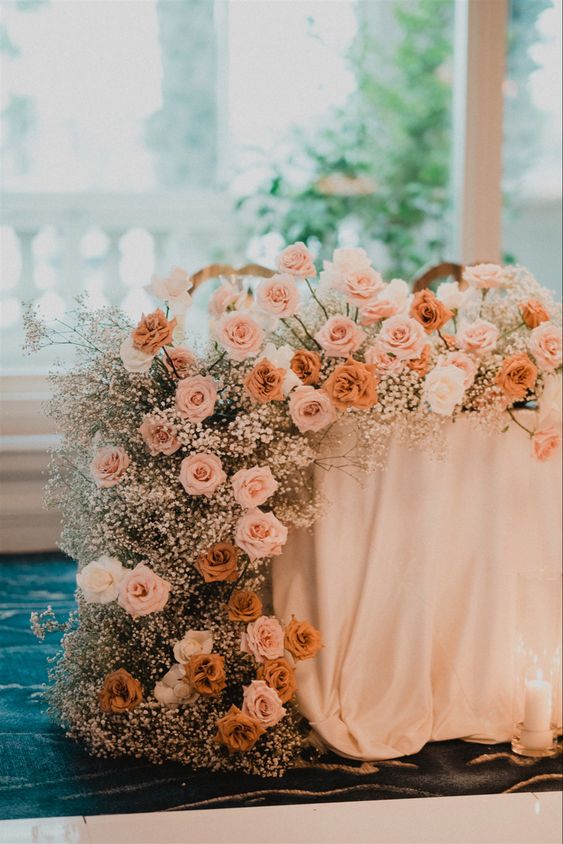 a cascading wedding centerpiece of white baby’s breath, white, blush and orange roses is amazing for a modern wedding