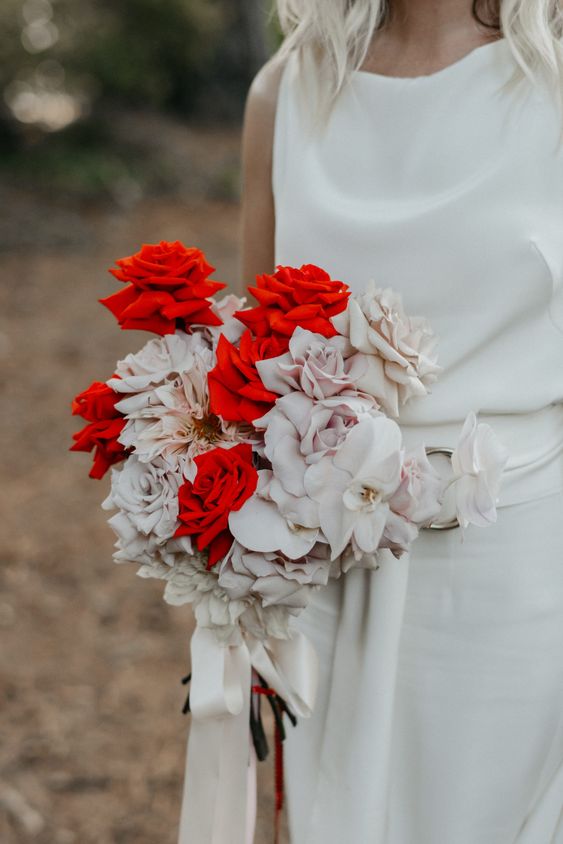 a chic and bold modern wedding bouquet of blush and red roses and some orchids is very sophisticated