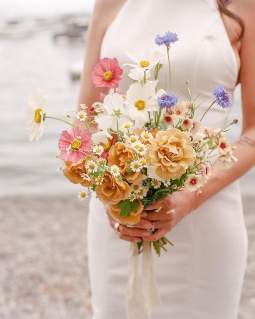 a colorful wedding bouquet of chamomiles, pink and white cosmos and some other blooms is lovely for summer