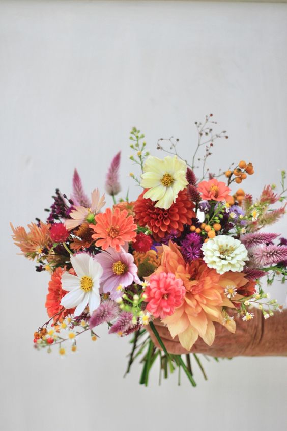 a colorful wedding bouquet of pink, white and orange cosmos, dahlias, dried grasses and berries is a cool solution for the fall