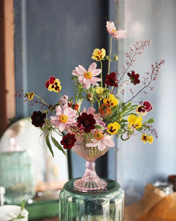 a colorful wedding centerpiece of pink cosmos, marigolds and various blooms in burgundy and yellow is a chic idea for the fall