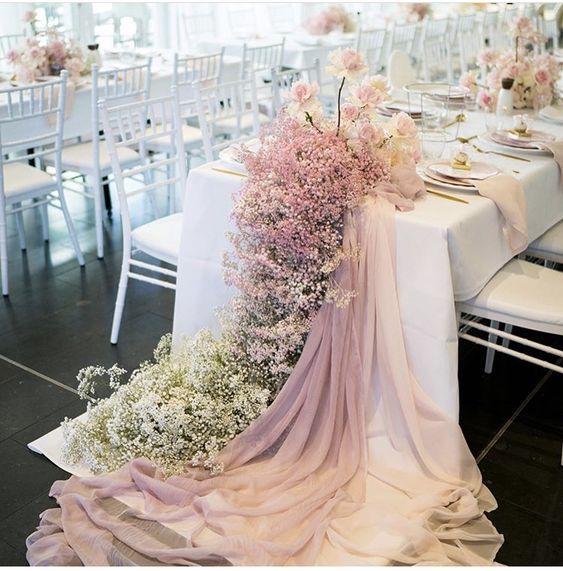 a cool cascading wedding centerpiece of pink and white baby’s breath and blush roses on the table is amazing for an elegant wedding