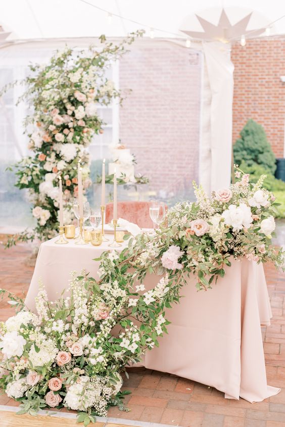 a creative lush cascading wedding centerpiece of white and blush blooms and greenery will fit a spring or summer wedding