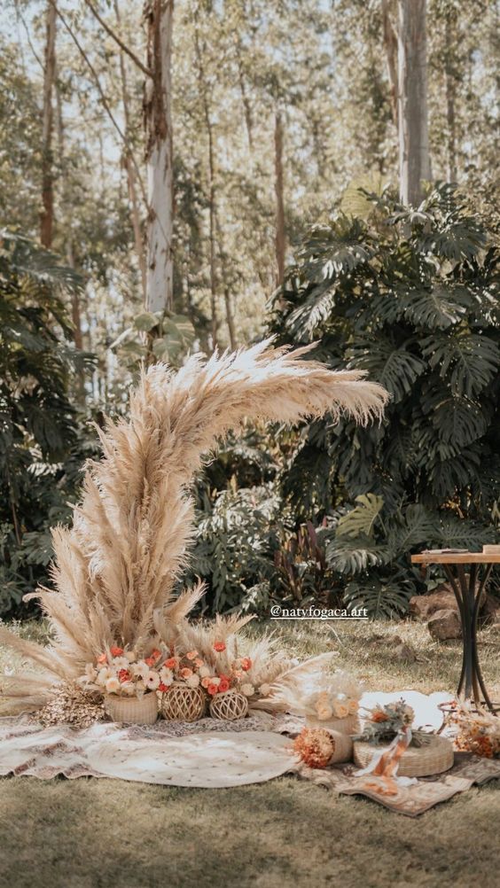 a crescent moon shaped wedding altar of pampas grass with some bold blooms at the base is amazing for a boho wedding