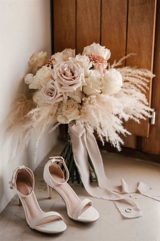a delicate neutral wedding bouquet of pampas grass, white and blush roses is a cool idea for a spring or summer wedding