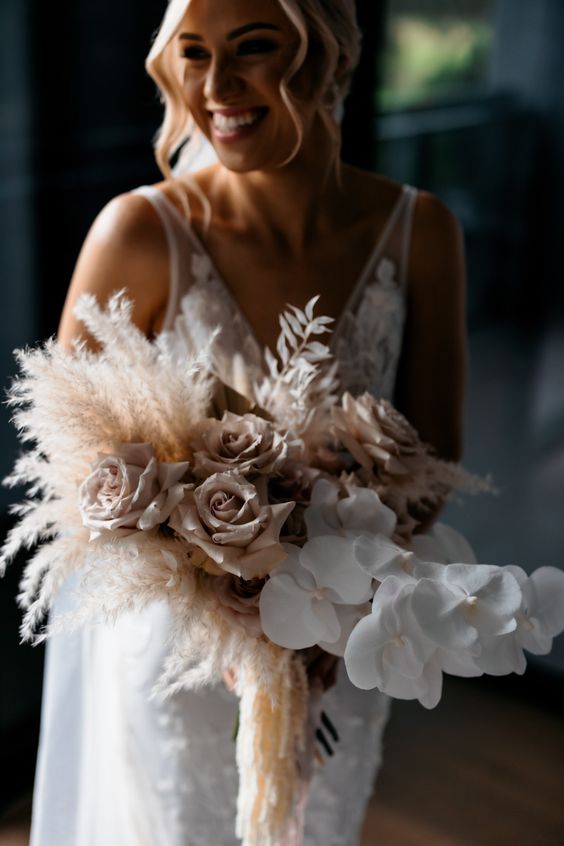 a delicate neutral wedding bouquet of white orchids, blush roses and pampas grass is a lovely spring or summer wedding idea