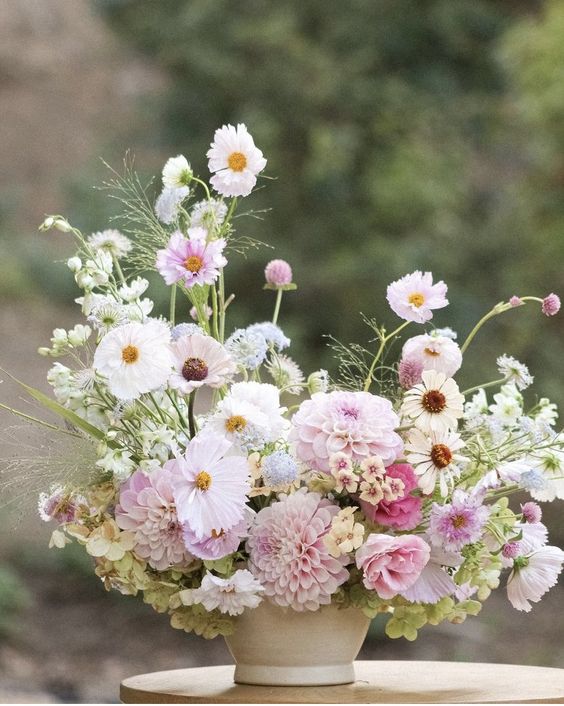 a dimensional wedding centerpiece of blush dahlias, cosmos and some fillers and greenery is cool for spring and summer