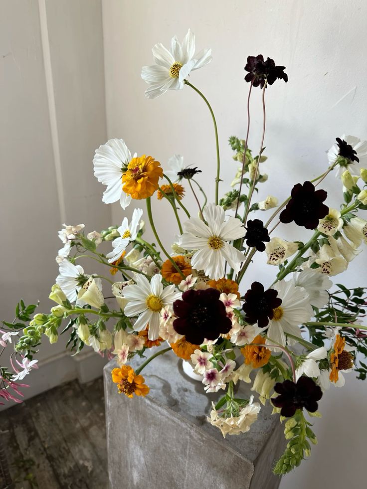 a dimensional wedding centerpiece of white cosmos, deep purple blooms and marigolds is amazing for the fall