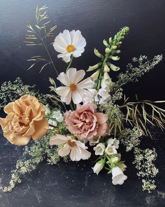 a dimensional wedding centerpiece of white cosmos, greenery, yellow and pink roses and fillers is a cool idea for summer