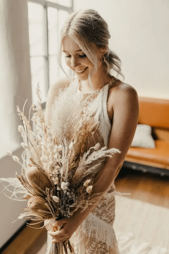 a dried boho wedding bouquet with bunny tails, pampas grass, proteas and dried foliage is a chic idea for a summer or fall wedding