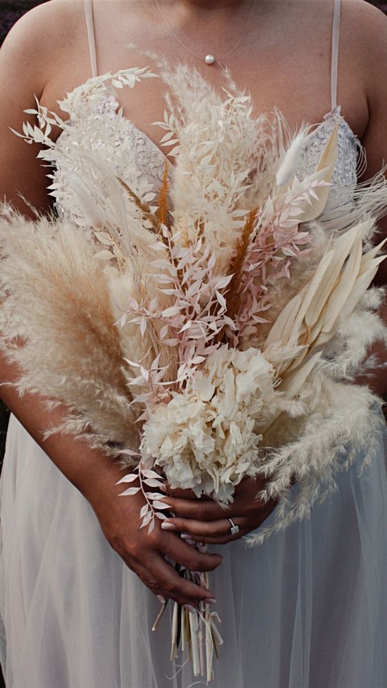 a dried wedding bouquet of blooms, leaves and pampas grass is a cool idea for a neutral boho wedding