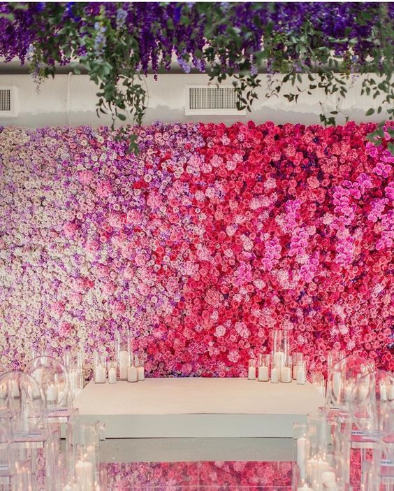 a fantastic floral ombre wedding wall from lilac and white to bold pink and red, with candles around is a fantastic idea for a colorful wedding
