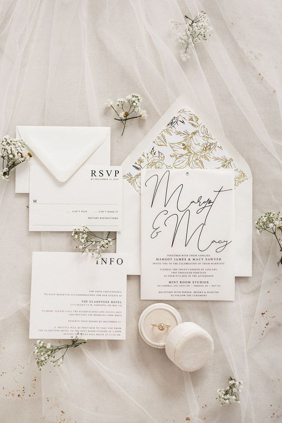 a glam white wedding invitation suite with black letters and calligraphy and an envelope with gold floral lining