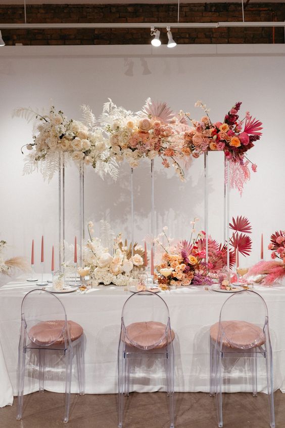 a gorgeous tall ombre wedding centerpiece from ivory to blush and pink and peachy, with roses and some fronds is wow