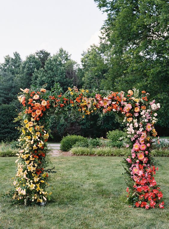 a gradient wedding arch from yellow to orange and coral plus red is a lovely and colorful decoration for a bright wedding