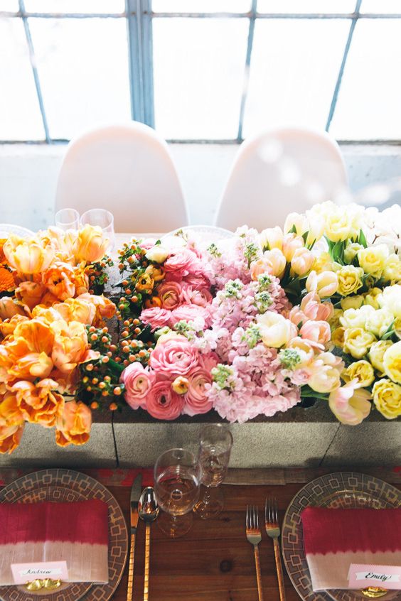 a gradient wedding centerpiece from orange to pink and yellow plus berries is a cool idea for a spring or summer wedding