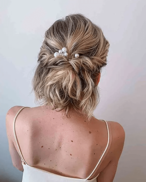a half updo with a bump on top and twists and waves and pearl hair pins is a cool idea for a bridal outfit