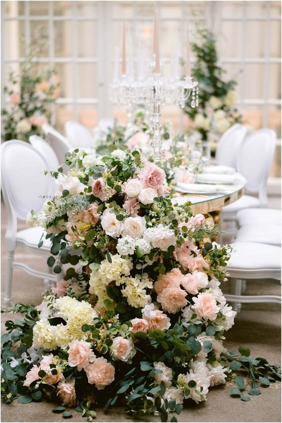 a lush cascading wedding centerpiece of white and blush roses, white hydrangeas, greenery for a garden wedding