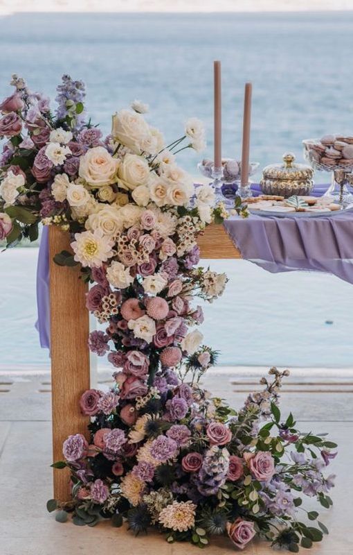 a lush cascading wedding centerpiece of white roses, lilac and purple mums, roses and ranunculus and some sweet peas plus greenery