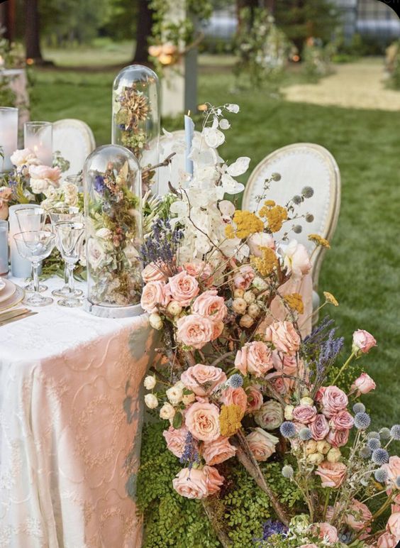 A lush fairy tale wedding centerpiece of pink roses, alliums, dried flowers and leaves is adorable
