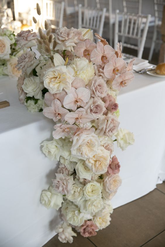 a lush neutral wedding centerpiece of blush orchids, white roses and some dried grasses is amazing for a neutral wedding with a touch of exquisiteness