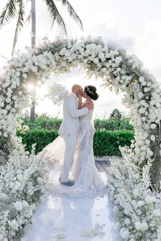 a lush round wedding arch decorated with white roses, hydrangeas adn dahlias and some white deliphinium is amazing for a wedding