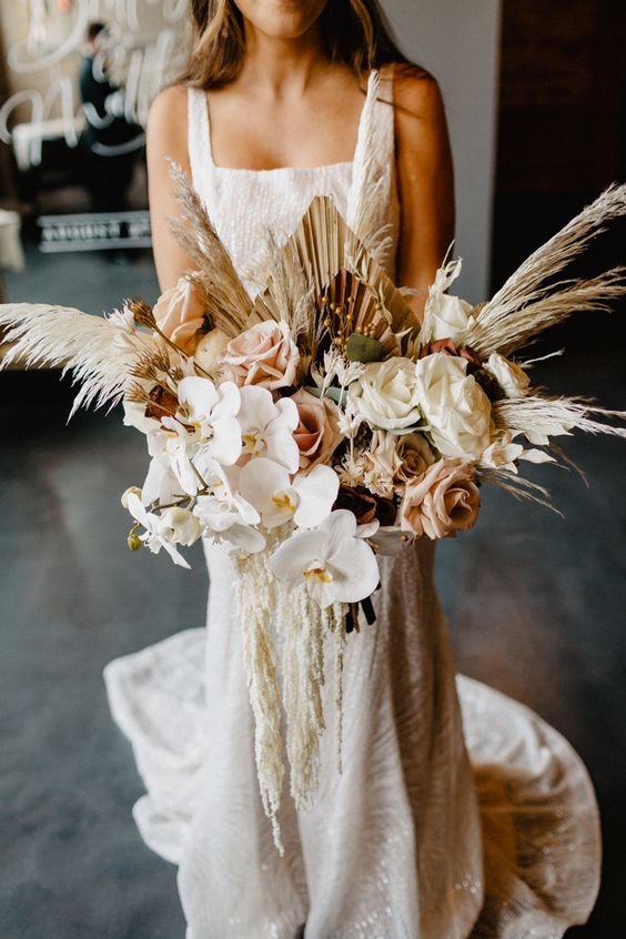 a lush wedding bouquet of white orchids, blush and white roses, pampas grass and fronds, amaranthus is amazing