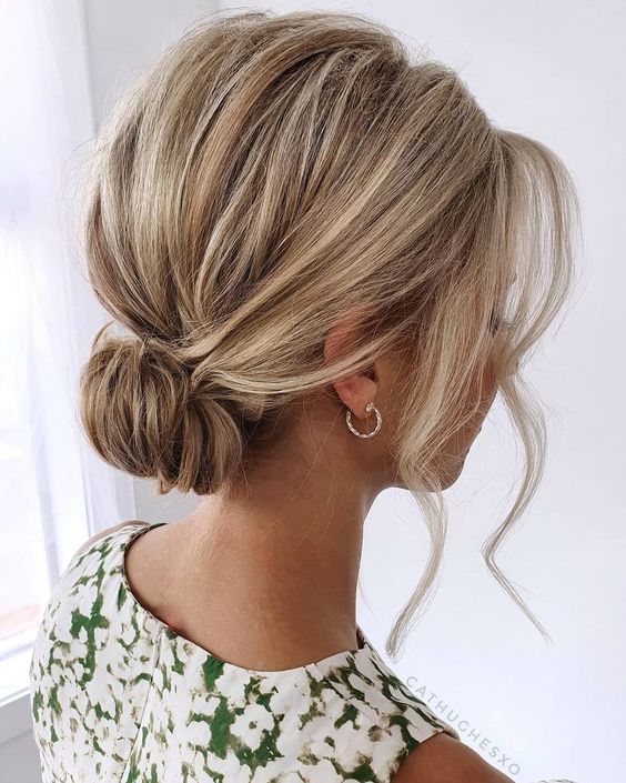 a messy wrapped updo with a bump on top and face-framing bangs is a cool and catchy hairstyle to rock