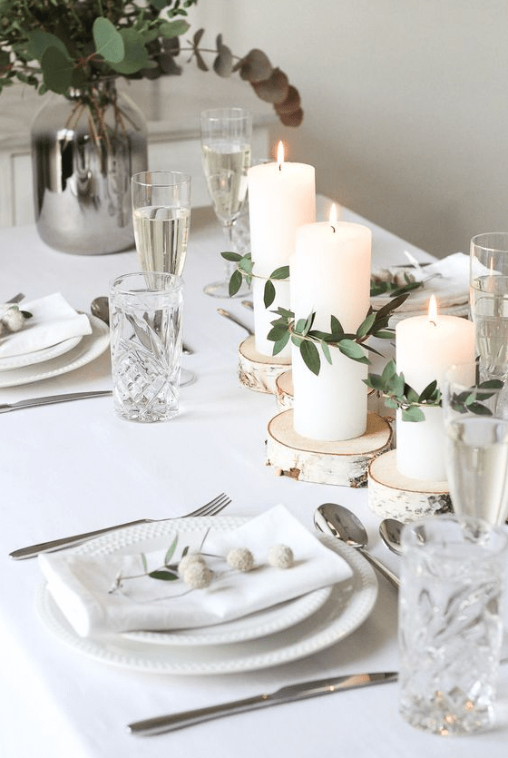 a minimalist and rustic Nordic wedding tablescape with wood slices and candles wrapped with eucalyptus, neutral porcelain and napkins