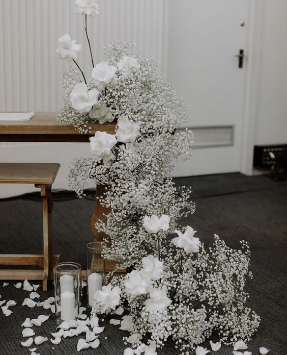 a modern cascading white wedding centerpiece of baby's breath and roses is a stylish and chic decoration for a modern wedding