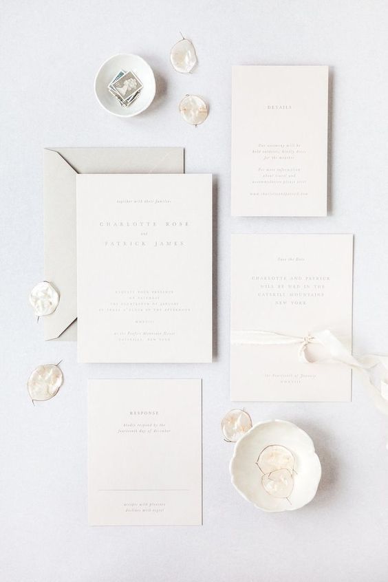 a modern to minimalist white wedding invitation suite with neutral letters and a grey envelope is a stylish and cool idea