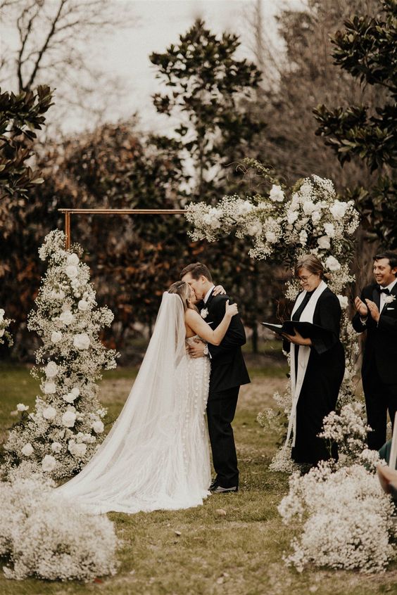 a modern wedding arch decorated with some greenery, baby’s breath and white blooms is a chic and catchy decor idea