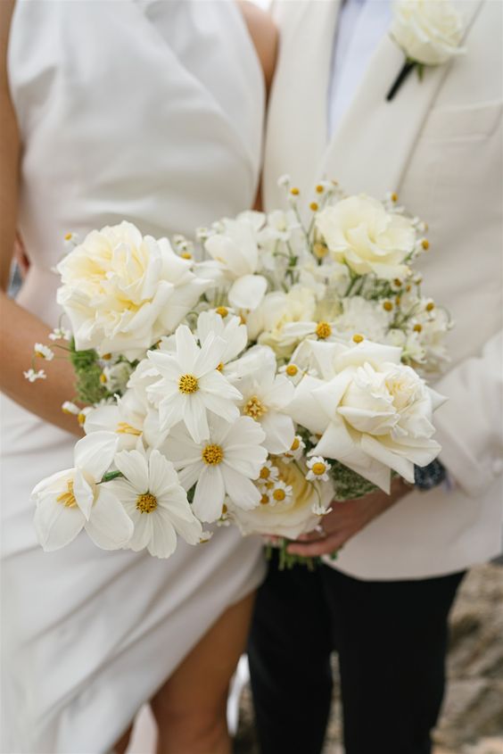 a modern white wedding bouquet of roses, cosmos and chamomiles is a lovely idea for any modern and neutral wedding