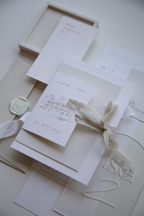 a modern white wedding invitation suite with neutral letters, some textural paper and ribbon is a cool solution for  a modern wedding