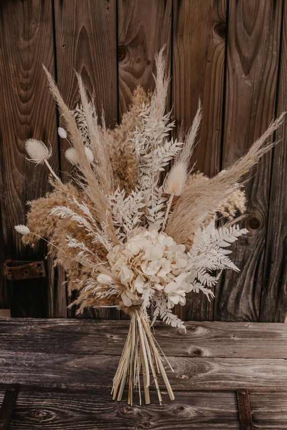 a neutral boho wedding bouquet of pampas grass, dried grasses and flowers is a stylish and chic idea