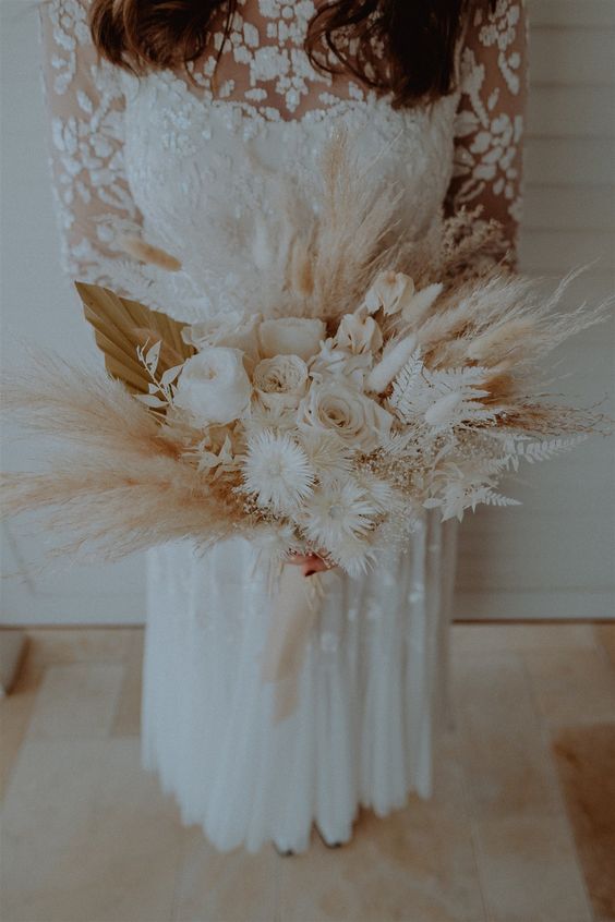 a neutral boho wedding bouquet of white roses, dried blooms, fronds and bunny tails, pampas grass is all cool