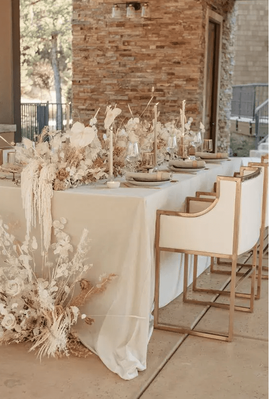 a neutral fall wedding tablescape with neutral candles, neutral dried blooms, grasses and leaves looks ethereal