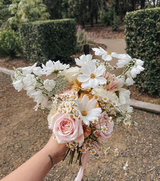a neutral wedding bouquet of cosmos, chamomiles, fillers and pink roses is a lovely idea for spring