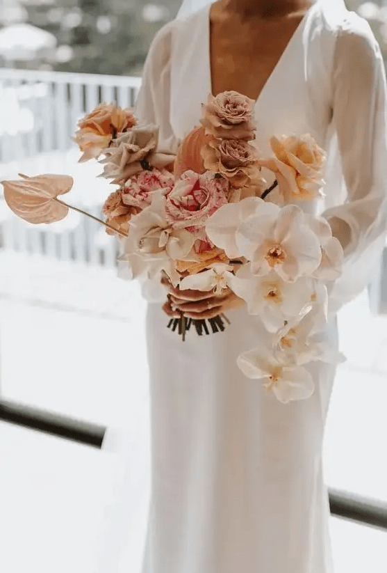 A neutral wedding bouquet of white and blush orchids, blush and white roses plus coffee colored ones and some anthurium