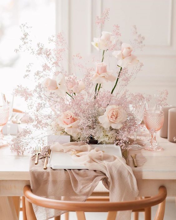 a pretty blush wedding centerpiece of roses and some baby's breath is a very delicate and chic decoration