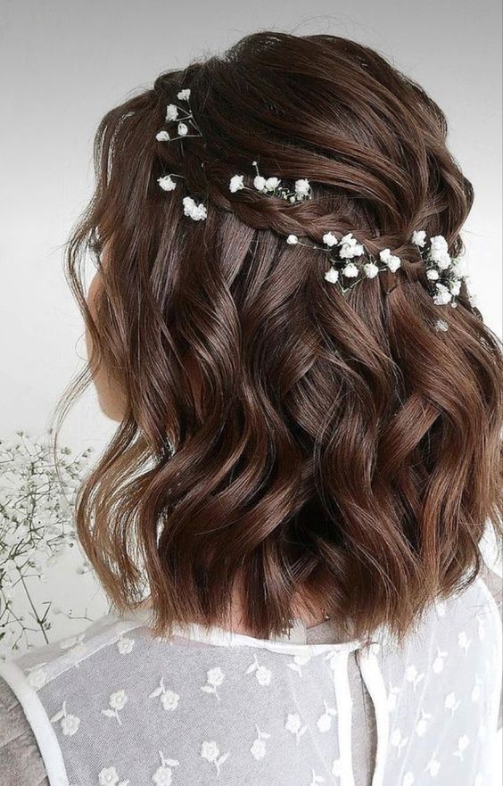 a refined wavy and volumetric half updo with a bump, a small braid with blooms and elegant waves down for a boho bride