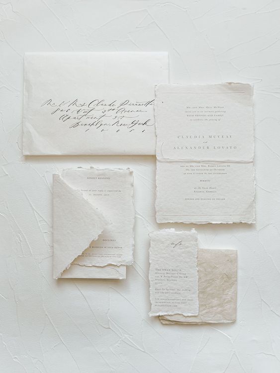 a refined white wedding invitation suite with textural paper and a raw edge, black lettering and calligraphy is lovely