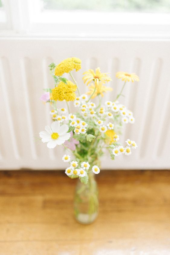 a relaxed summer wedding centerpiece of white cosmos, chamomiles and mimosa blooms is a cool arrangement to DIY