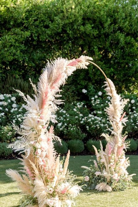 a round pampas grass wedding arch done in neutrals and pink is super creative and very eye-catchy