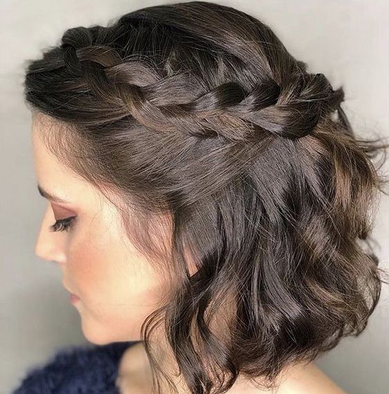 a short wavy half updo with a braided halo and waves down is a stylish and cool idea for a wedding