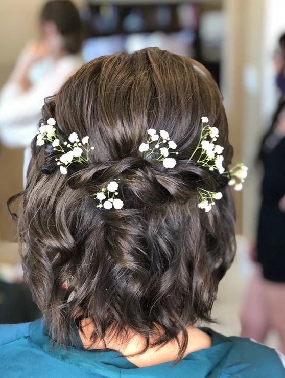 a short wavy half updo with a bump on top and a twisted halo plus some fresh blooms tucked in