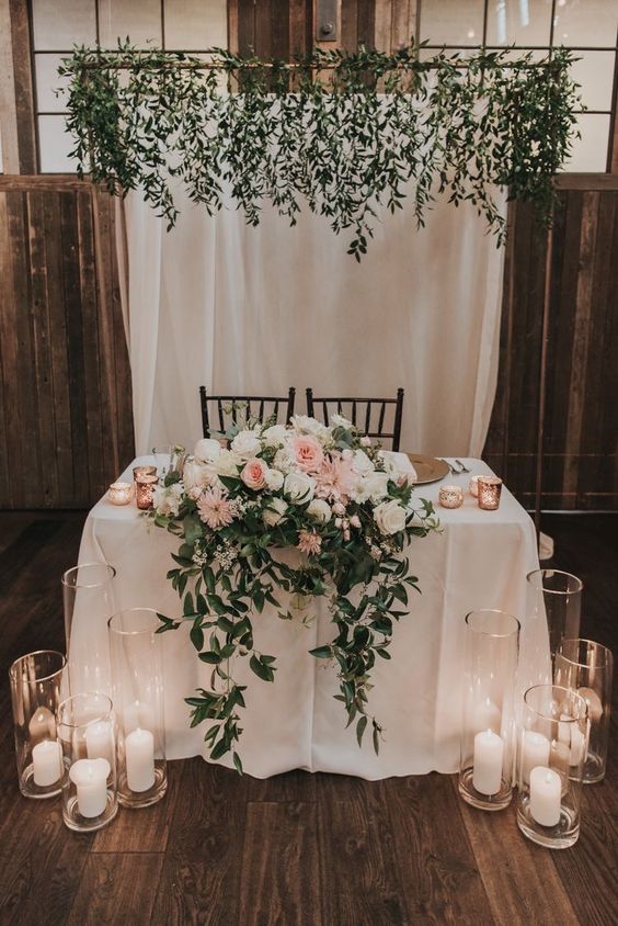 a simple and lush cascading wedding centerpiece of white and blush roses, dahlias and greenery will fit a rustic wedding